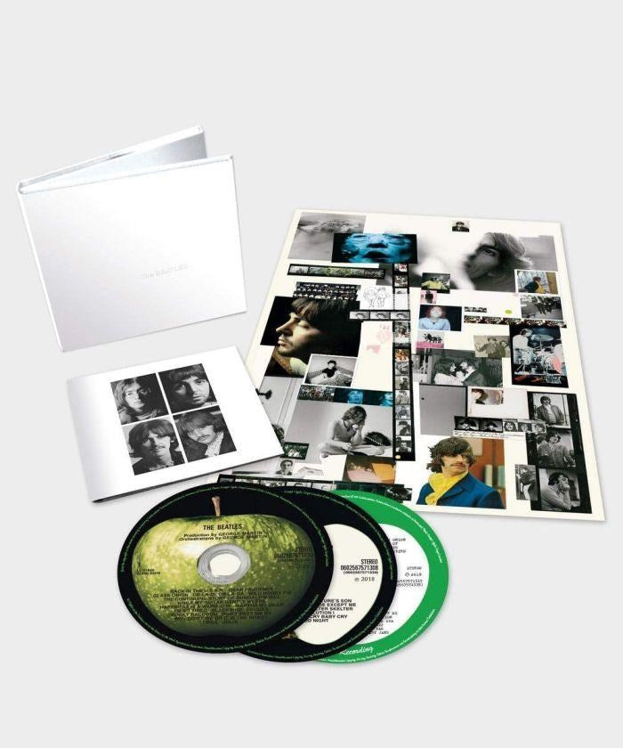 The Beatles White Album Super Deluxe box set featuring a minimalist white box, large photo books with archival band images, booklet inserts, and multiple CDs laid out on a white background, official expanded edition music release from Utopia Records.